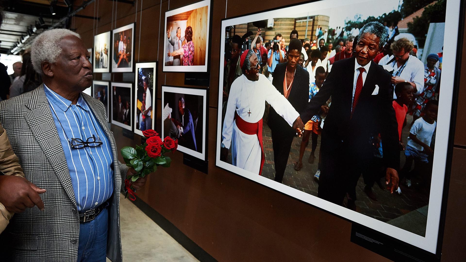 Peter Magubane blickt bei einer Ausstellung seiner Fotografien auf ein Bild, das Nelson Mandela und Desmond Tutu zeigt. Peter Magubane blickt bei einer Ausstellung seiner Fotografien auf ein Bild, das Nelson Mandela und Desmond Tutu zeigt.