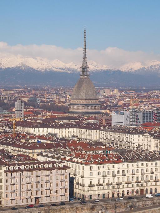 Die Stadt Turin, fotografiert aus der Vogelperspektive. Im Hintergrund ist eine schneebedeckte Bergkette zu sehen.