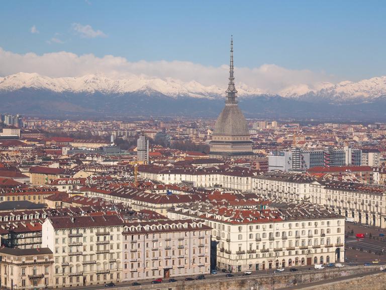 Die Stadt Turin, fotografiert aus der Vogelperspektive. Im Hintergrund ist eine schneebedeckte Bergkette zu sehen.