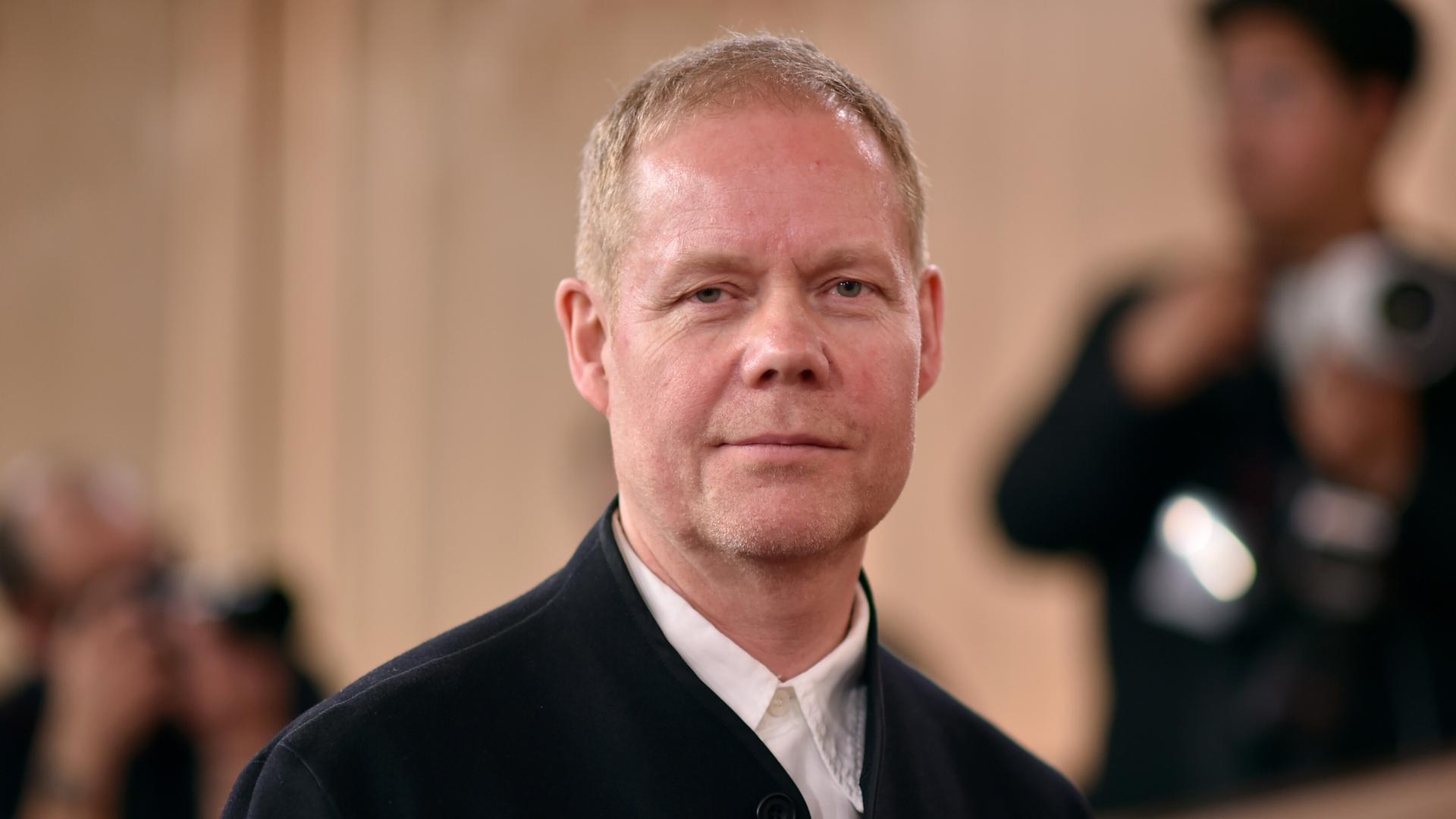 Max Richter schaut in die Kamera und lächelt.