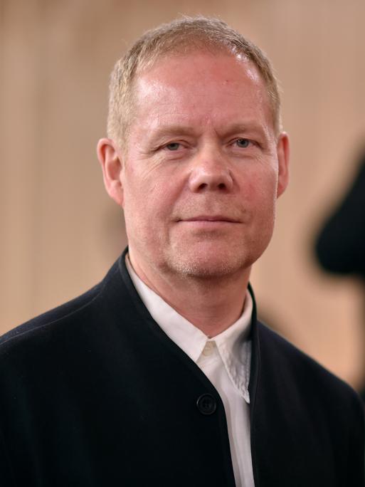 Max Richter schaut in die Kamera und lächelt.