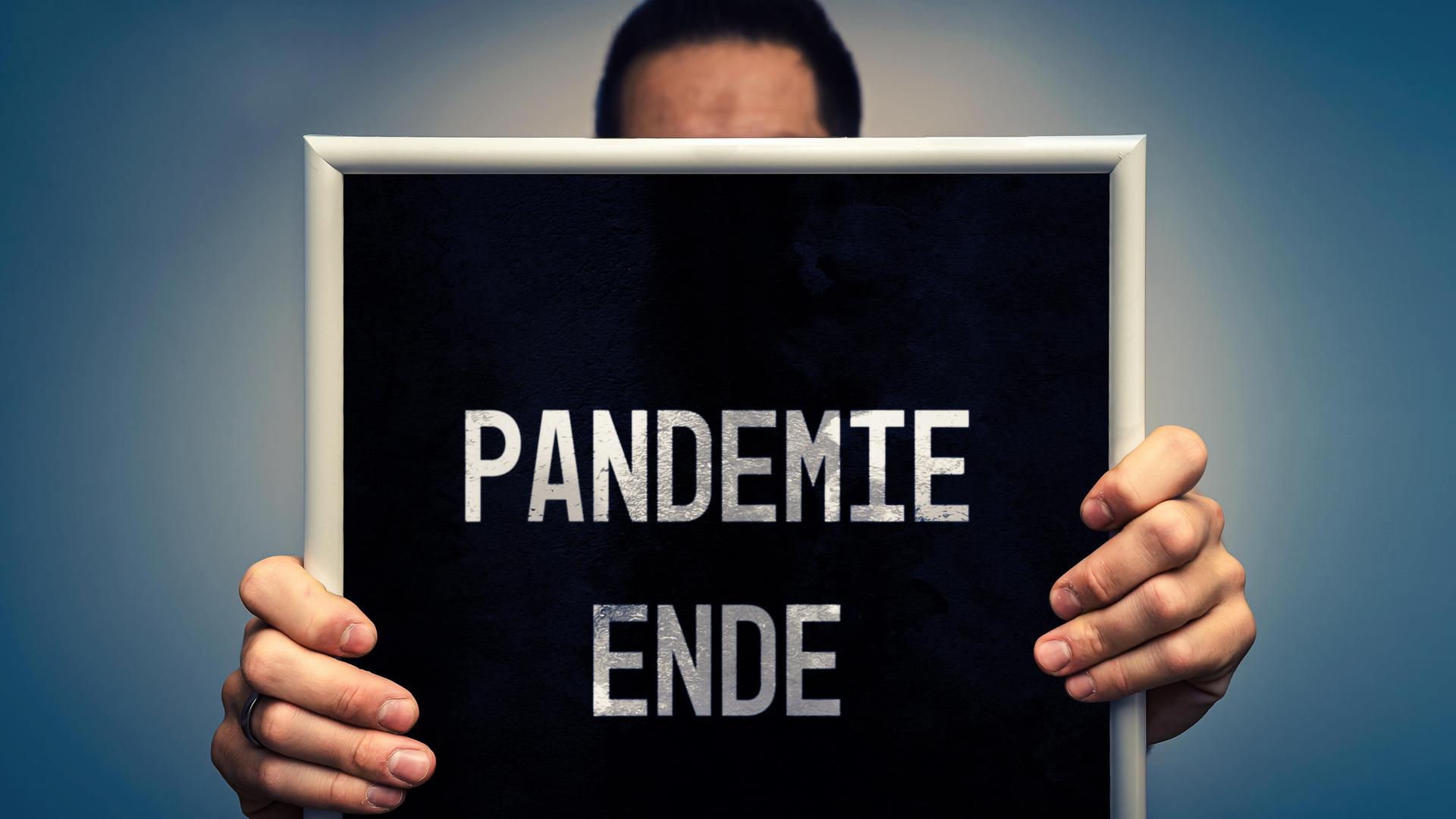Ein Mann hält ein Schild mit der Aufschrift "Pandemie Ende". 