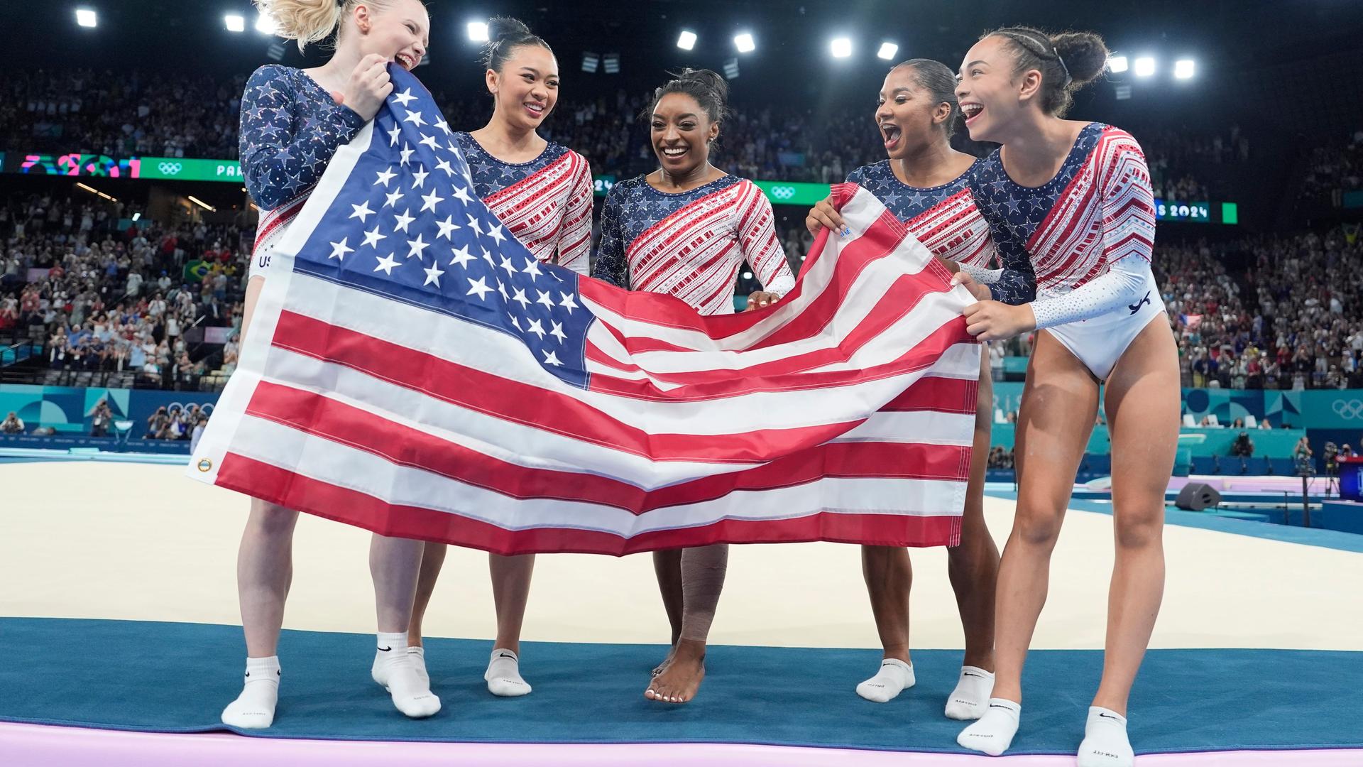 Jade Carey, Suni Lee, Simone Biles, Jordan Chiles und Hezly Rivera jubeln. Jade Carey, Suni Lee, Simone Biles, Jordan Chiles und Hezly Rivera jubeln.