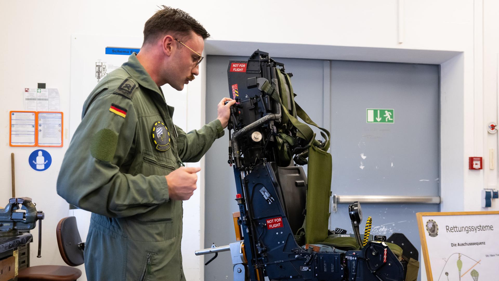 Hauptfeldwebel Patrik Scheibe erklärt während der Sommerreise der Bundesverteidigungsministerin am taktischen Luftwaffen Geschwader 74 die Funktion von einem Schleudersitz eines Eurofighters.