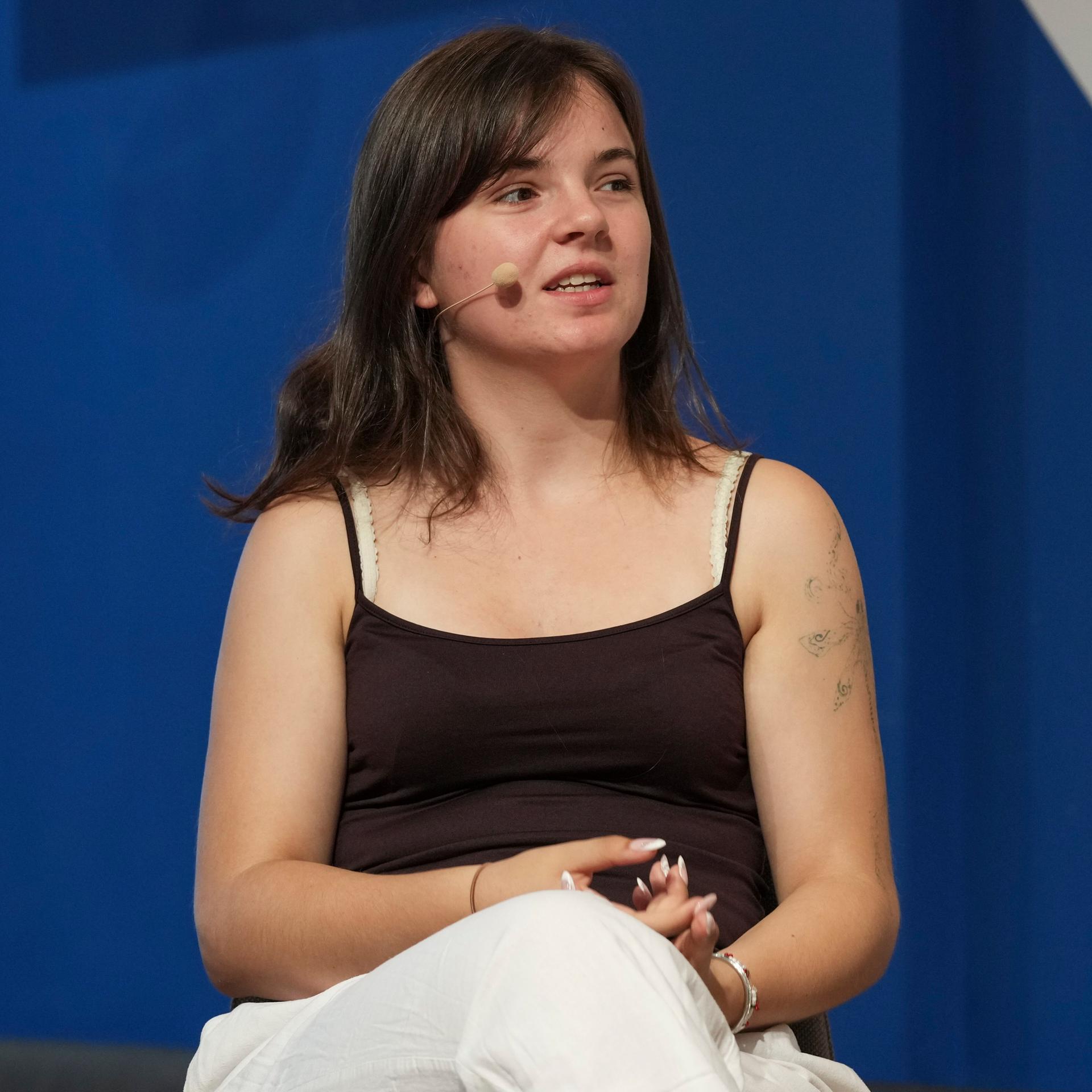 Lilli Berthold, stellvertretende Generalsekretärin der Bundesschülerkonferenz, spricht bei einer Veranstaltung auf einem Podium.