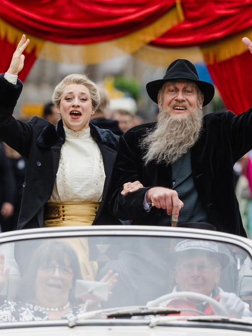 Als Theaterherzog und Helene Freifrau von Heldburg gekleidete Teilnehmer winken beim Festumzug zum 200. Geburtstag von Georg II. von Sachsen-Meiningen aus einem Oldtimer.