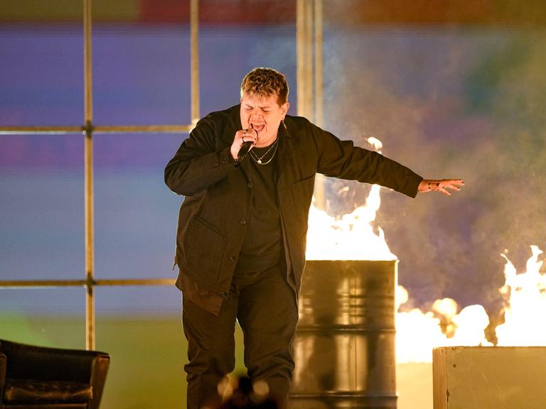 Der deutsche Sänger Isaak auf der Bühne des ESC neben einer Blechtonne mit Feuer 