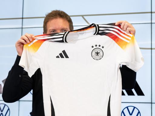 Bundestrainer Julian Nagelsmann hält auf einer Pressekonferenz das neue offizielle EM-Trikot des DFB-Teams hoch.