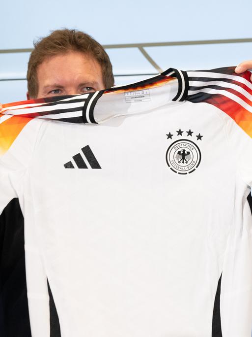 Bundestrainer Julian Nagelsmann hält auf einer Pressekonferenz das neue offizielle EM-Trikot des DFB-Teams hoch.