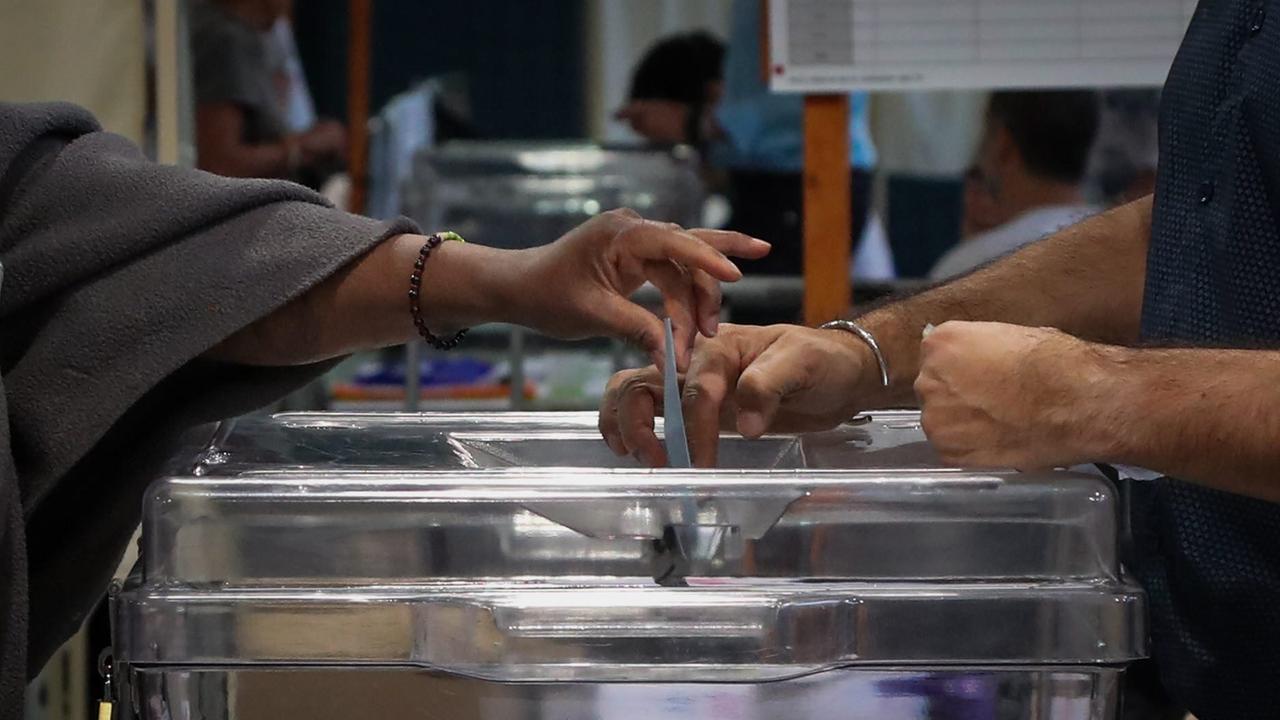 Eine Hand wirft einen Wahlzettel in eine Urne. Eine Hand wirft einen Wahlzettel in eine Urne.