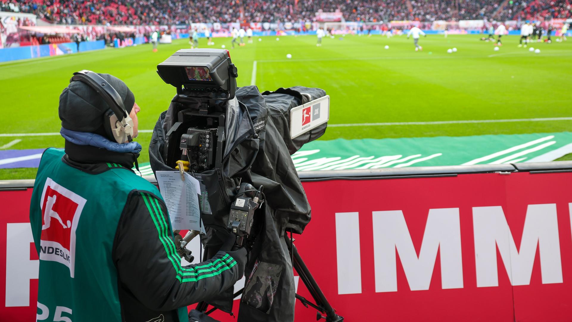 Ein Kameramann arbeitet am Spielfeldrand während eines Bundesligaspiels. 