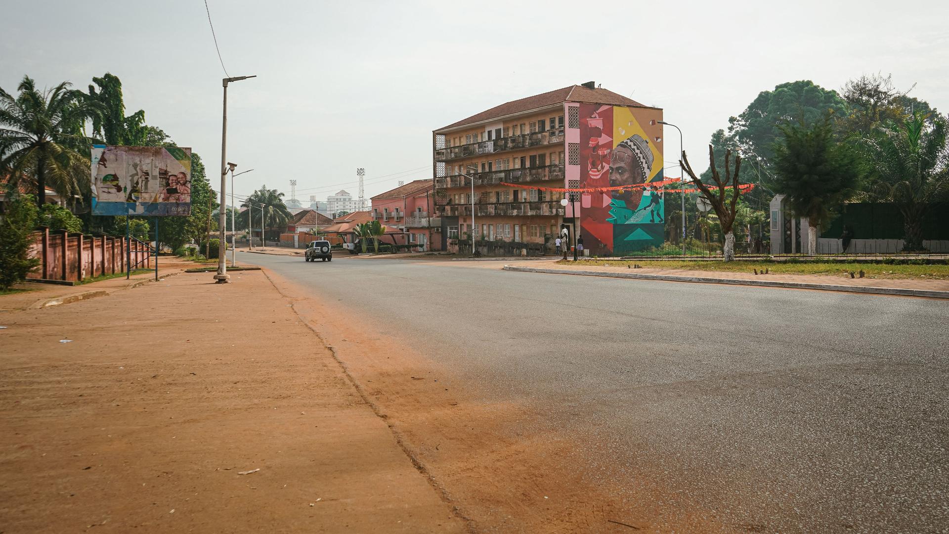 Eine völlig leere Straße in Bissau, nur ein Auto fährt.