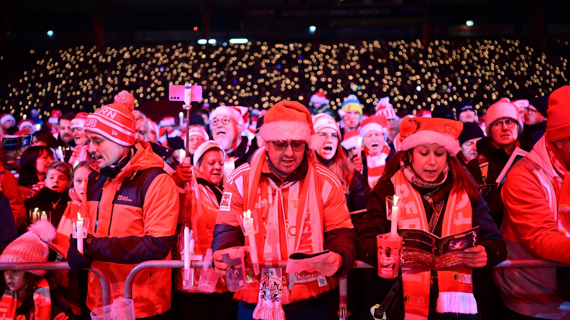 Weihnachtssingen im Stadion von Union Berlin. Viele Menschen tragen Nikolausmützen. 