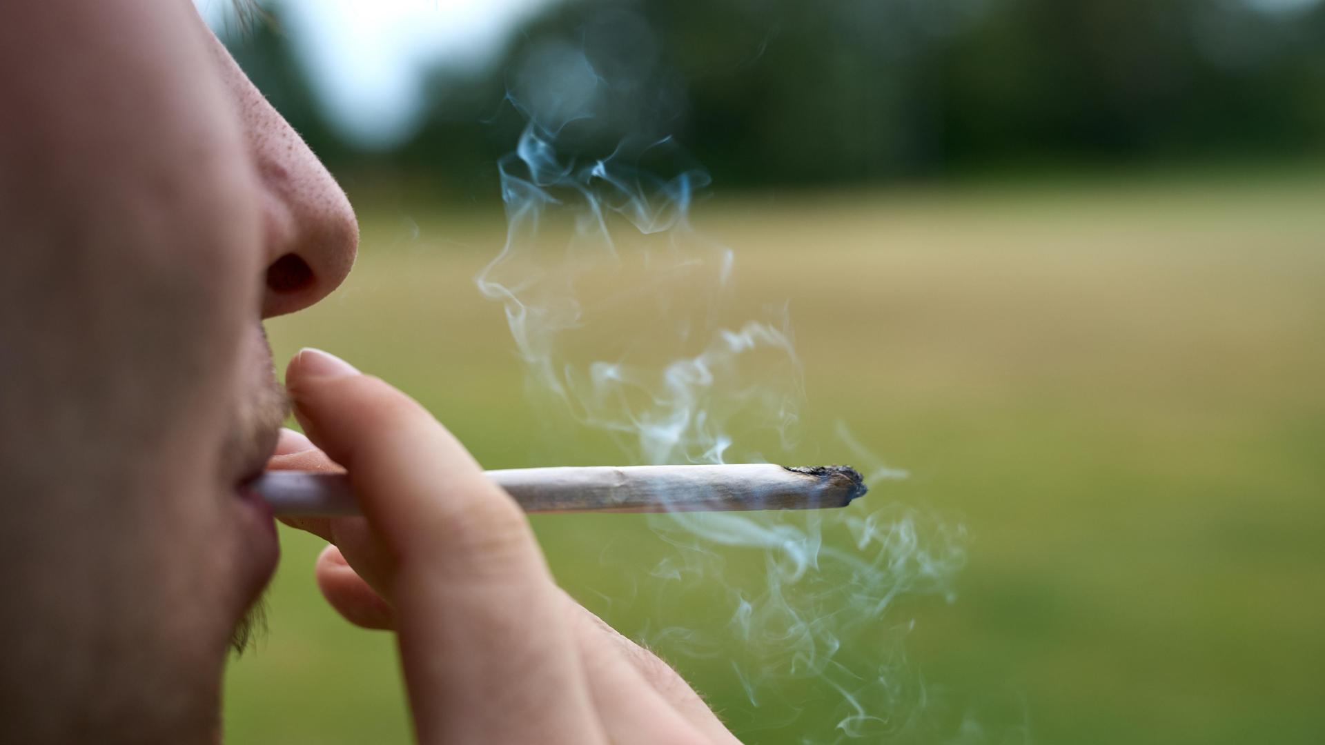 Ein junger Mann zieht an einem Cannabis-Joint.