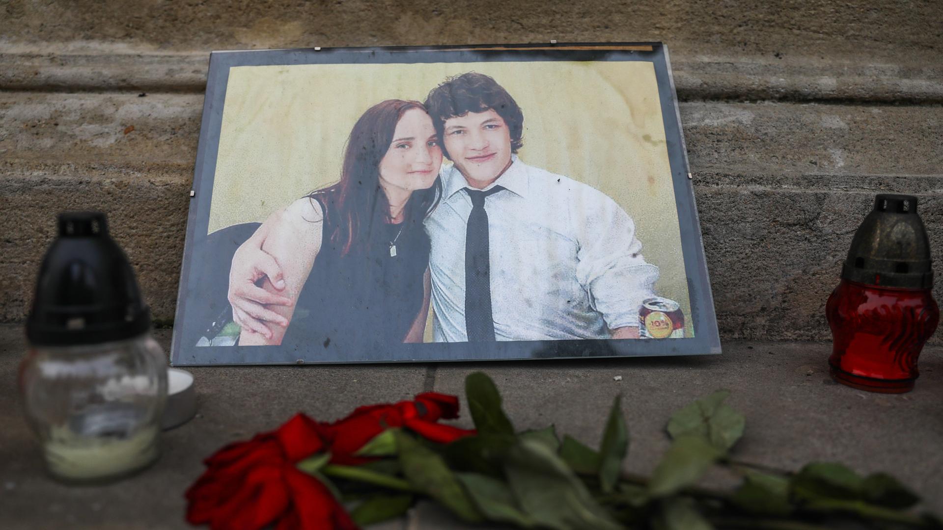 Zwei Kerzen stehen neben einer Fotografie des Investigativjournalisten Jan Kuciak und seiner Verlobten Martina Kusnirova, die 2018 in der Slowakei ermordet wurden. Vor dem Bild liegt eine rote Rose. 