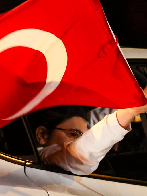 Aus einem Auto mit türkischer Fahne ragt eine Hand, die den sogenannten Wolfsgruß macht.