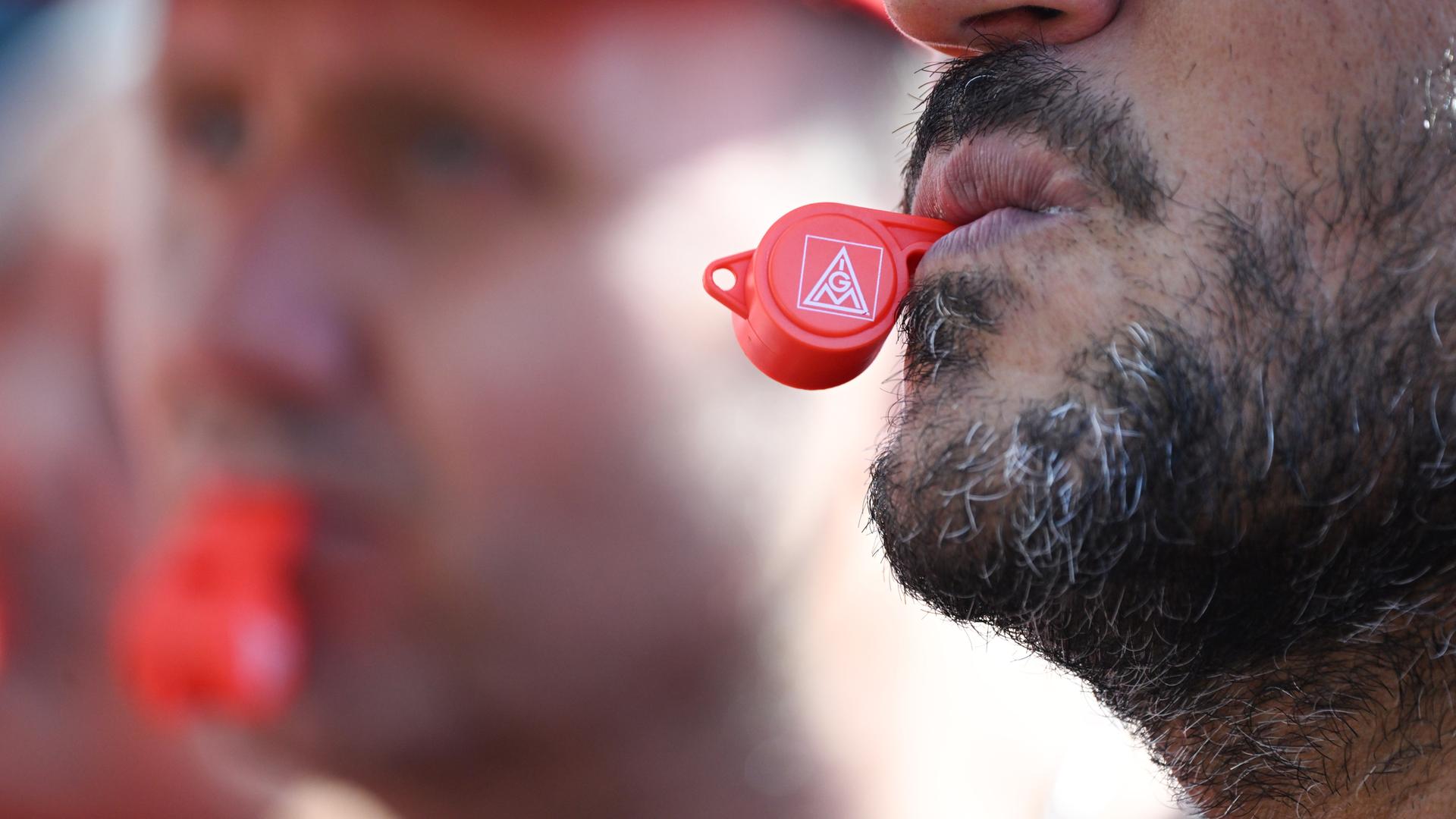 Zwei Männer halten IG-Metall-Pfeifen zwischen den Lippen. Zwei Männer halten IG-Metall-Pfeifen zwischen den Lippen.