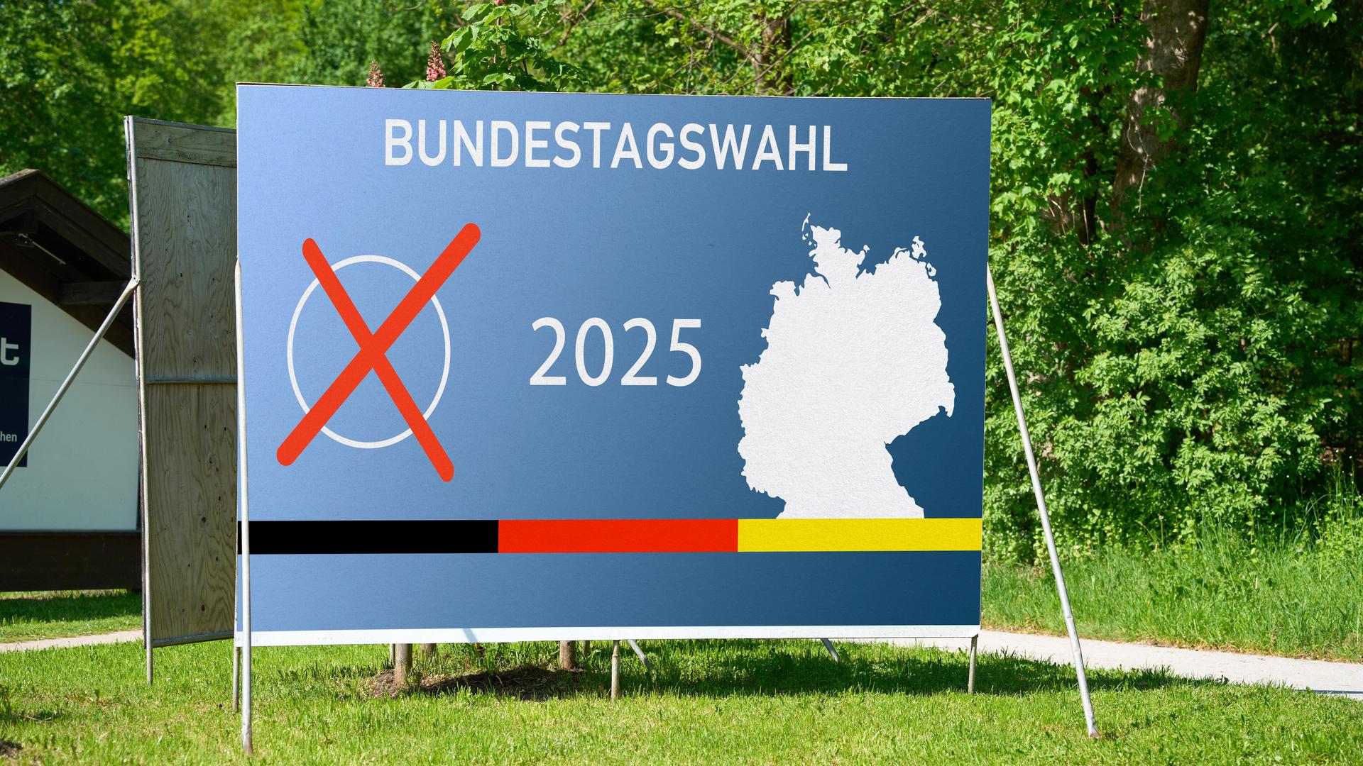 Ein Wahl-Plakat steht auf einer grünen Wiese. Es zeigt eine Deutschland-Karte und den Schrift-Zug Bundestags-Wahl 2025.