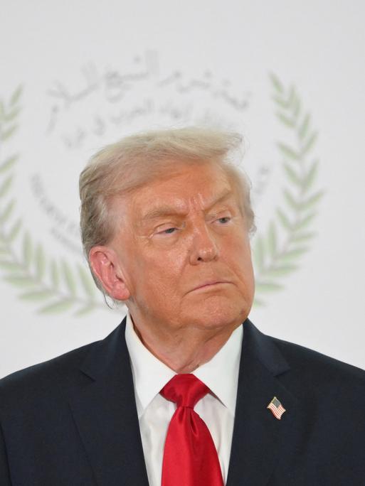US-Präsident Donald Trump posiert beim Gaza-Friedensgipfel in Scharm el-Scheich für ein Foto. Im Hintergrund ist das Logo des Gipfels zu sehen, das seinen Kopf umrahmt.