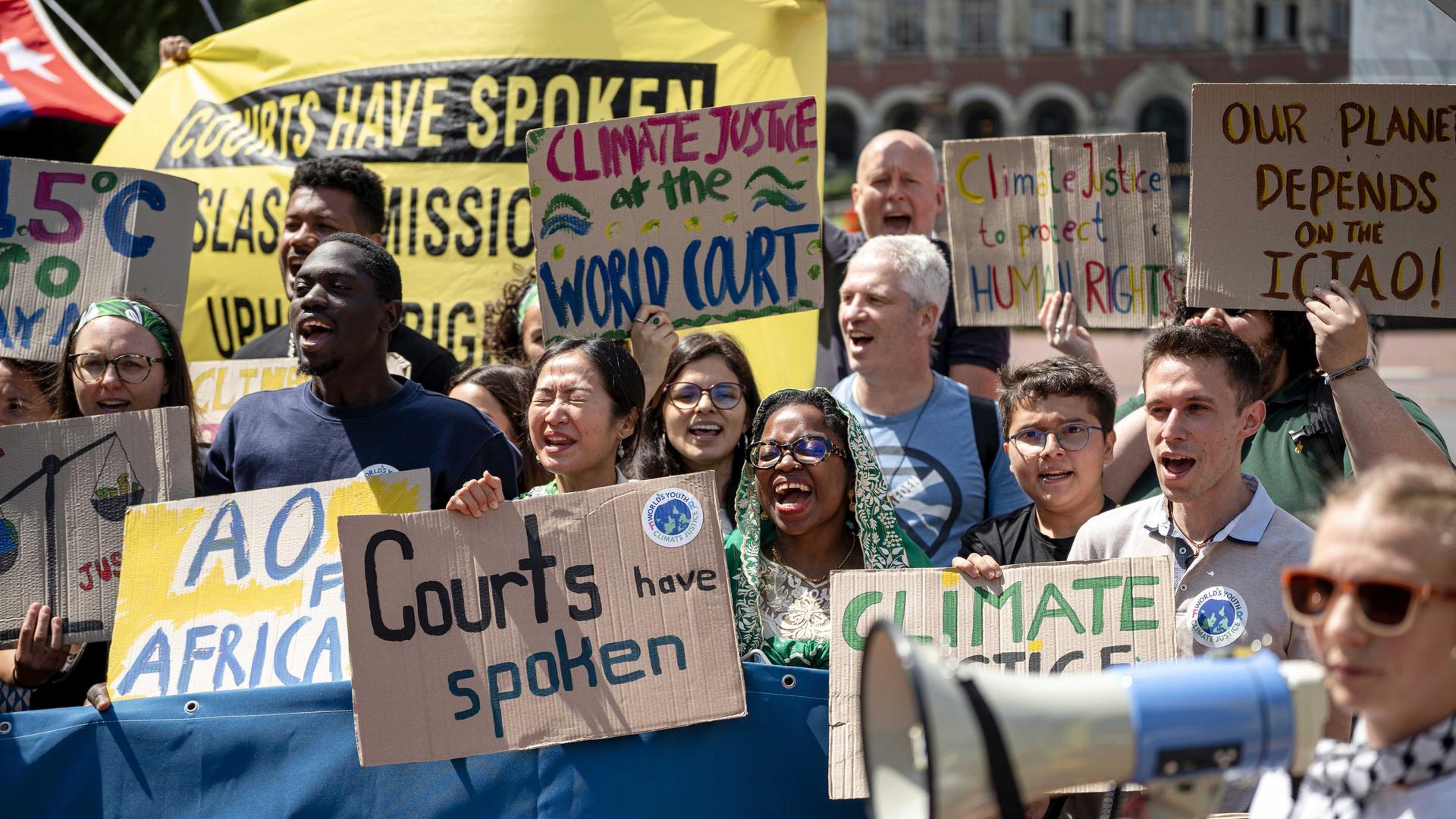 Demonstranten halten vor dem Internationalen Gerichtshof in Den Haag Schilder mit "Climate Justice" (dt. Klimagerechtigkeit) und "Court has spoken" (dt. Das Gericht hat gesprochen) (23.7.2025)