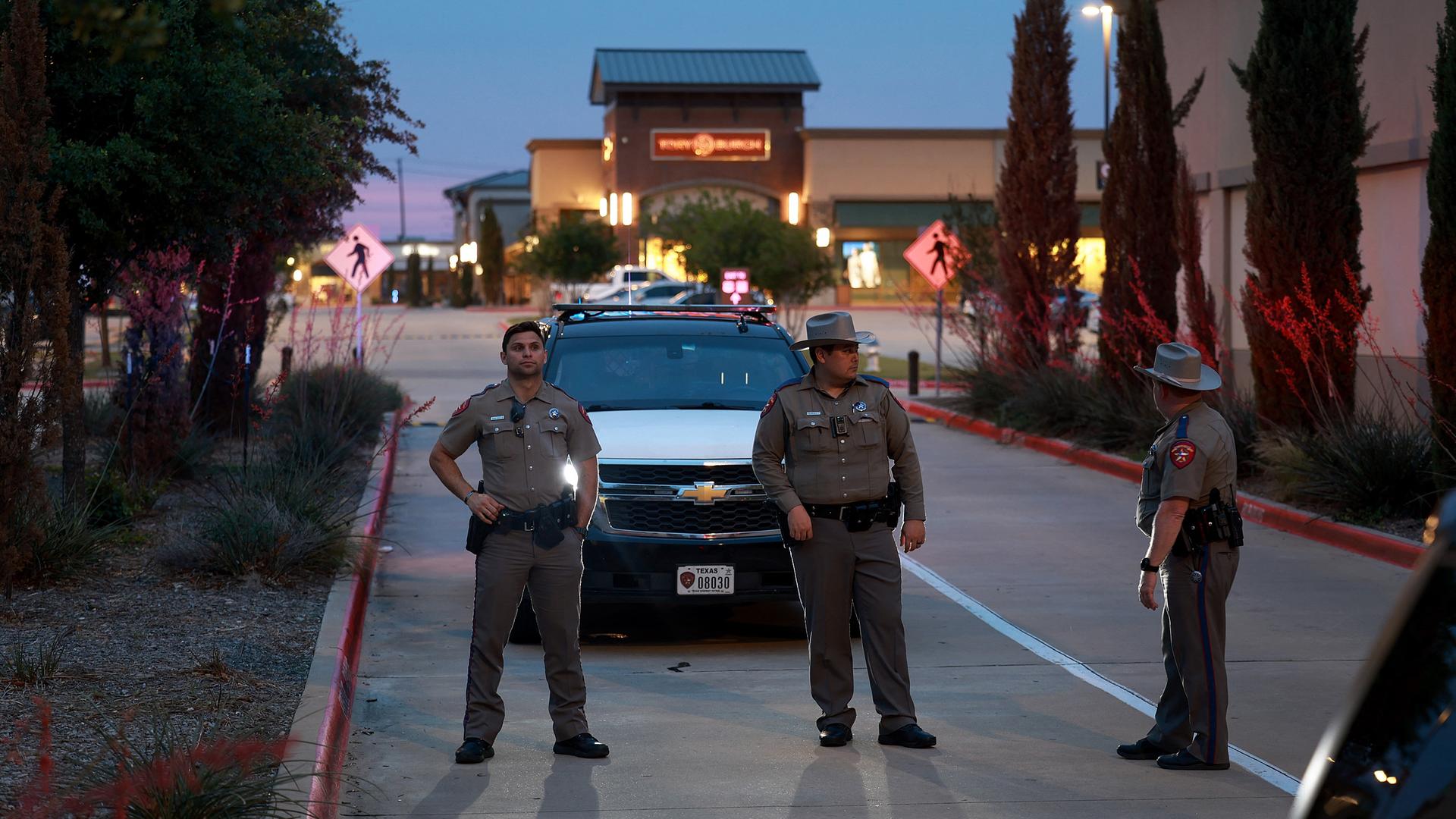 Drei US-Polizeibeamte stehen vor einem Dienstwagen und blockieren damit den eingang des Einkaufszentrums.