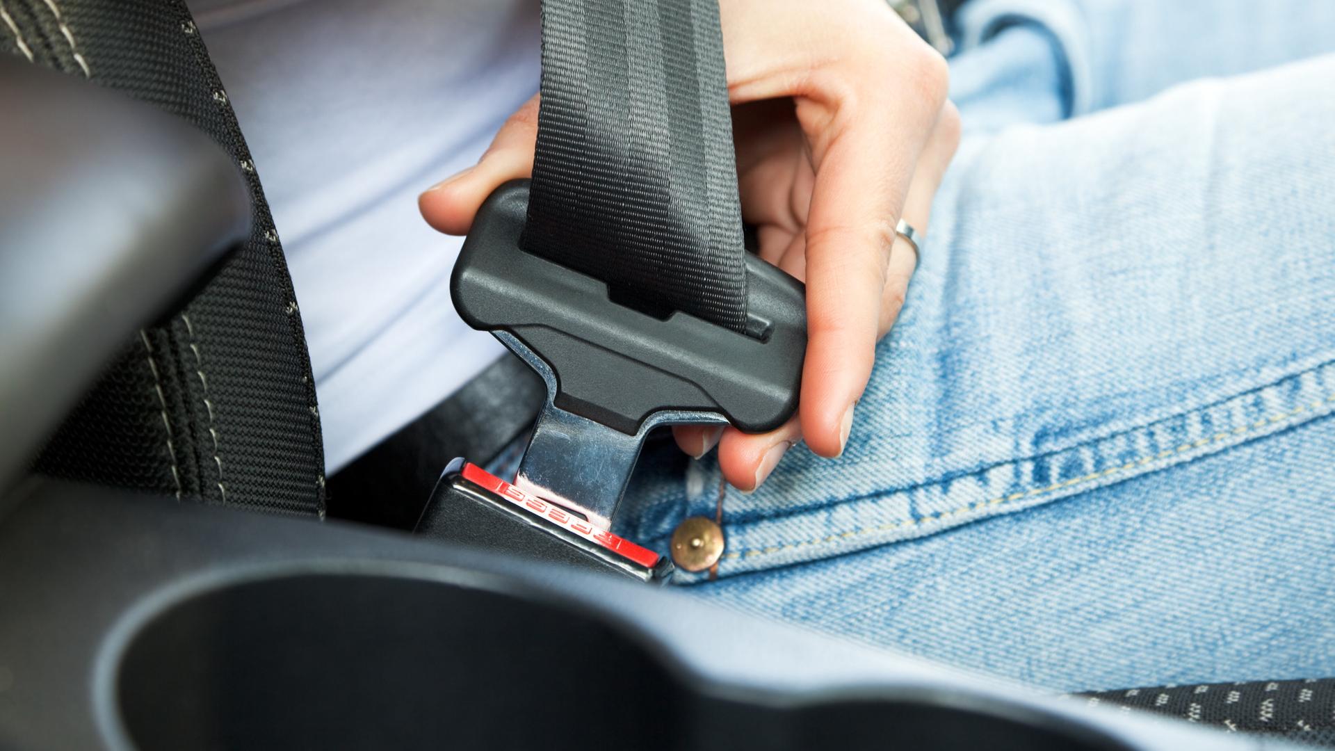 Eine Nahaufnahme von einem Sicherheitsgurt in einem Auto, den eine Person anlegt Eine Nahaufnahme von einem Sicherheitsgurt in einem Auto, den eine Person anlegt