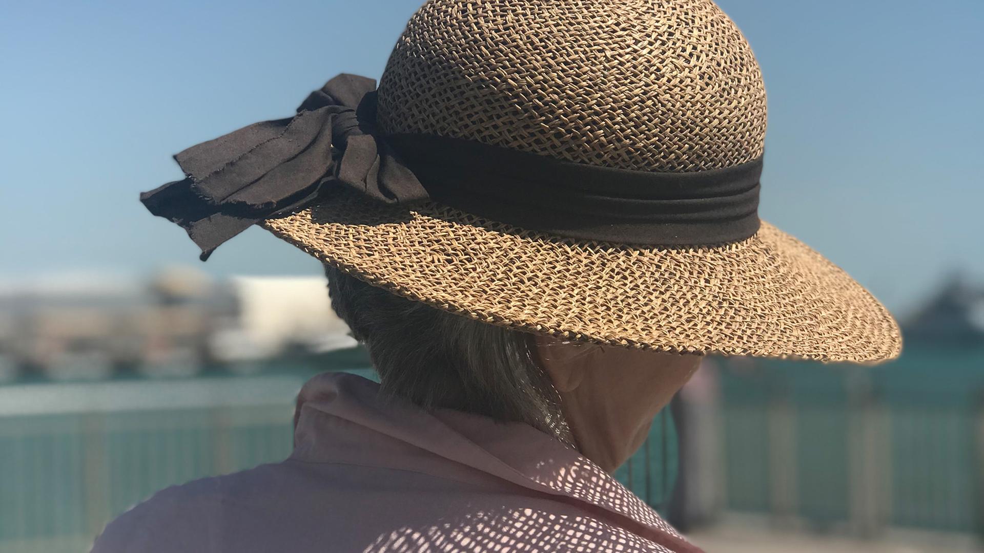 Der Kopf einer älteren Frau, die einen Strohhut trägt.