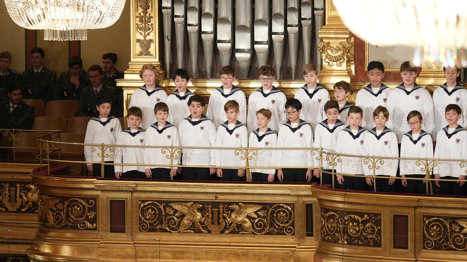 Singender Chor in Matrosen-Uniformen auf einer vergoldeten Empore vor Orgelpfeifen