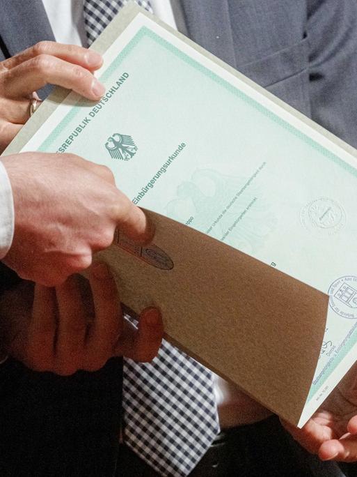 Eine Einbürgerungsurkunde der Bundesrepublik Deutschland wird bei einem Festakt im Hamburger Rathaus an eine Person übergeben stammt.