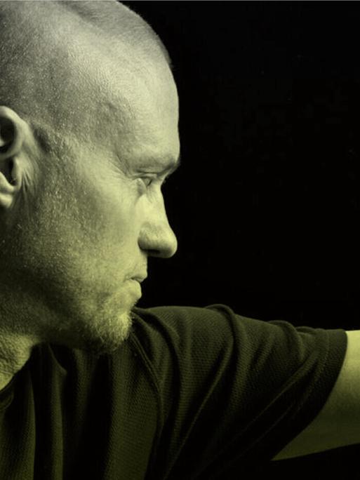 Porträt von Tim Friede, um dessen ausgestreckten Arm sich eine Wasserkobra schlängelt.