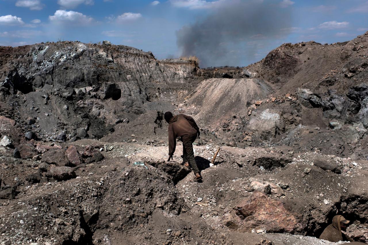 Ein Mann klettert über dunkle, steinige Hänge einer Kupfer- und Kobaltmine in Kawama. 