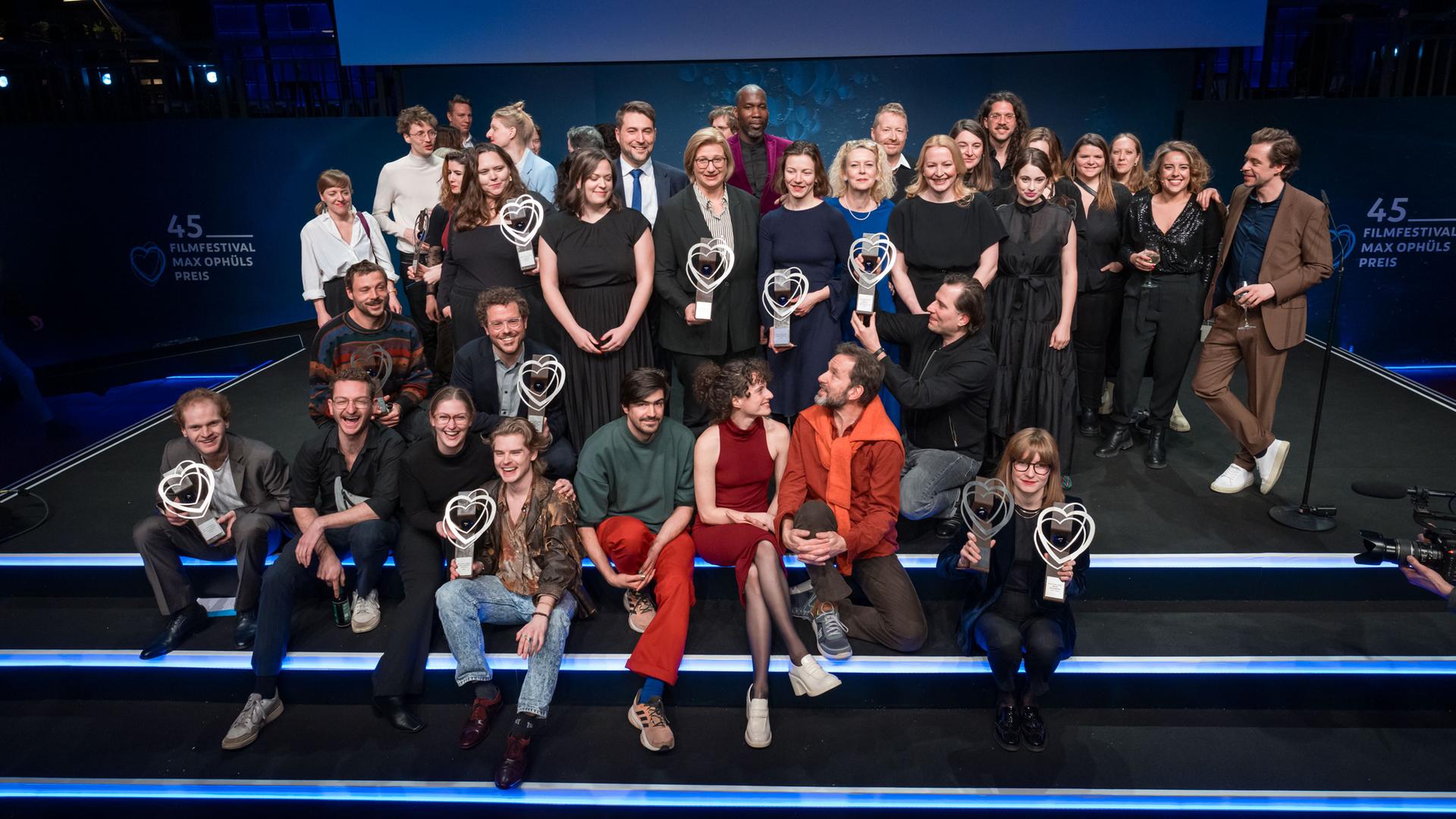 Preisträger des 45. Filmfestival Max Ophüls Preis stehen für ein Gruppenfoto auf der Bühne zusammen.