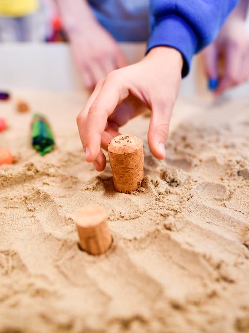 Eine Kinderhand greift nach einem Korken, der in einem Sandkasten steckt. Es handelt sich um den ersten Inklusionsspielplatz für Schulkinder. Eine Kinderhand greift nach einem Korken, der in einem Sandkasten steckt. Es handelt sich um den ersten Inklusionsspielplatz für Schulkinder.