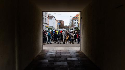 Blick durch eine dunkle Hauseinfahrt auf die Teilnehmerinnen und Teilnehmer einer Demonstration.