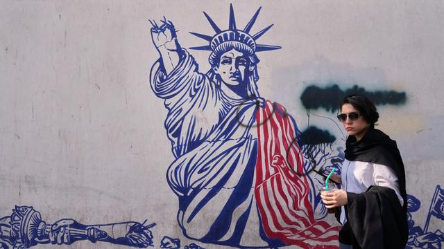 Wandbild an der früheren US-Botschaft in Teheran zeigt die Freiheitsstatue mit abgeschlagenem Arm. Davor geht eine Frau spazieren.