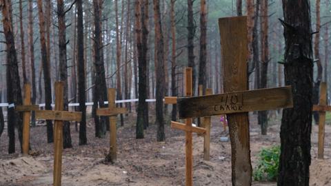 Holzkreuze stehen in einem Waldstück bei Isjum/ Ukraine.
