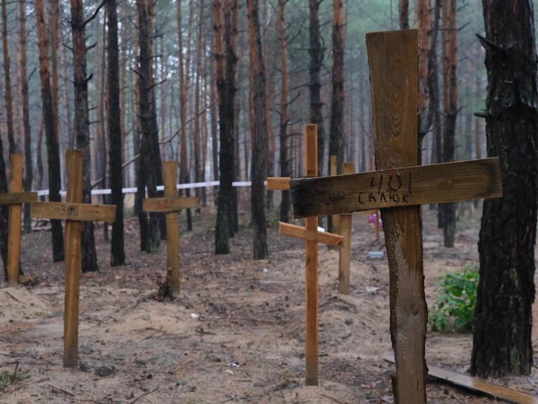 Holzkreuze stehen in einem Waldstück bei Isjum/ Ukraine.