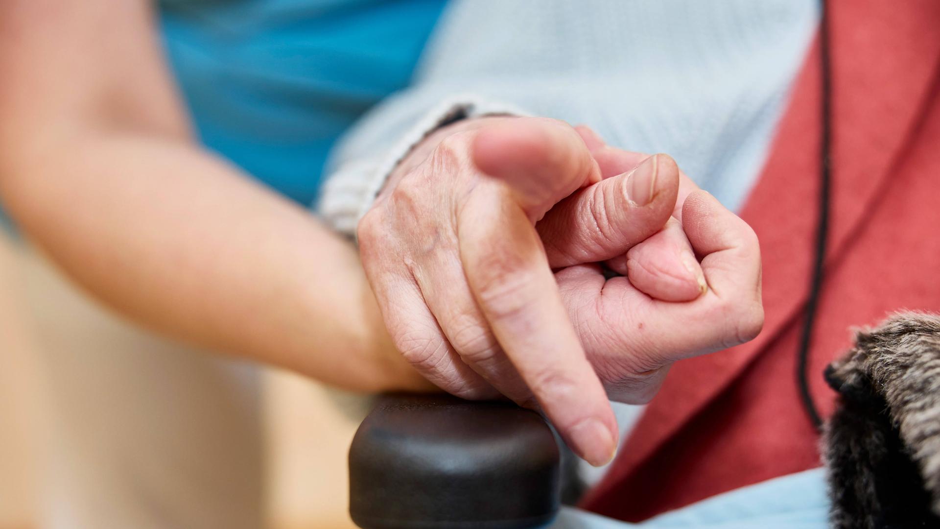 Die hand einer Pflegerin hält die Hand eines alten Menschen.