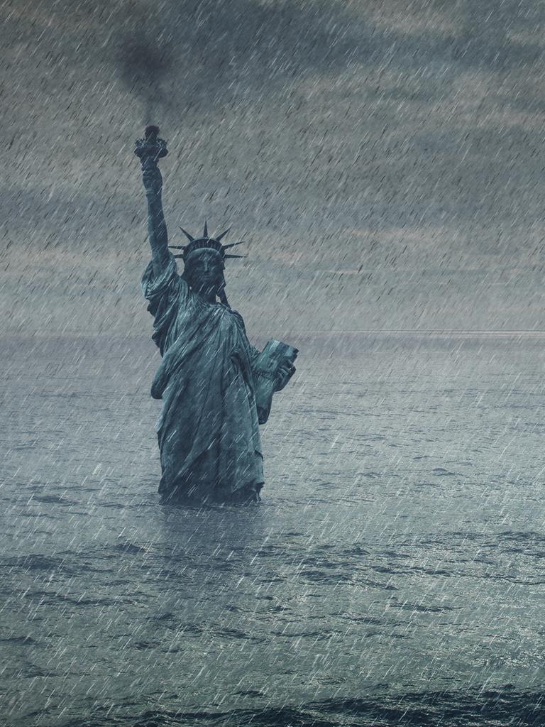 Eine Fotomontage/Illustration der Freiheitsstatue in New York. Es regnet und die Statue geht im Hochwasser unter.