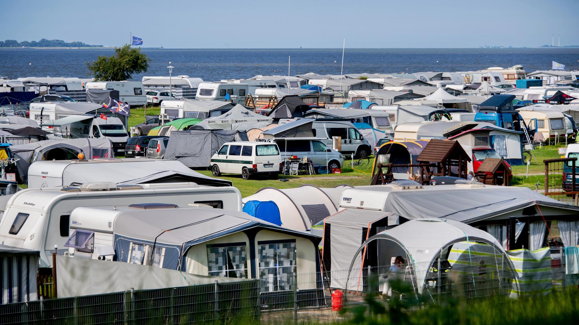Wohn-Wagen, Wohn-Mobile und Zelte stehen bei sonnigem Wetter auf einem Camping-Platz an der Nordsee. 