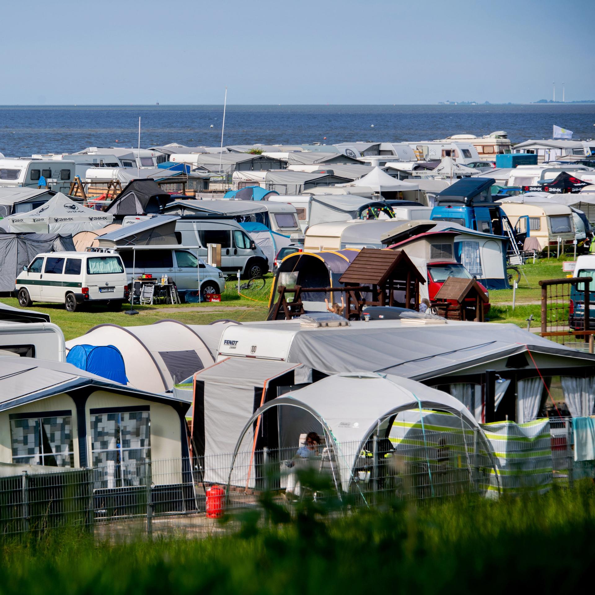 Wohn-Wagen, Wohn-Mobile und Zelte stehen bei sonnigem Wetter auf einem Camping-Platz an der Nord-See. 