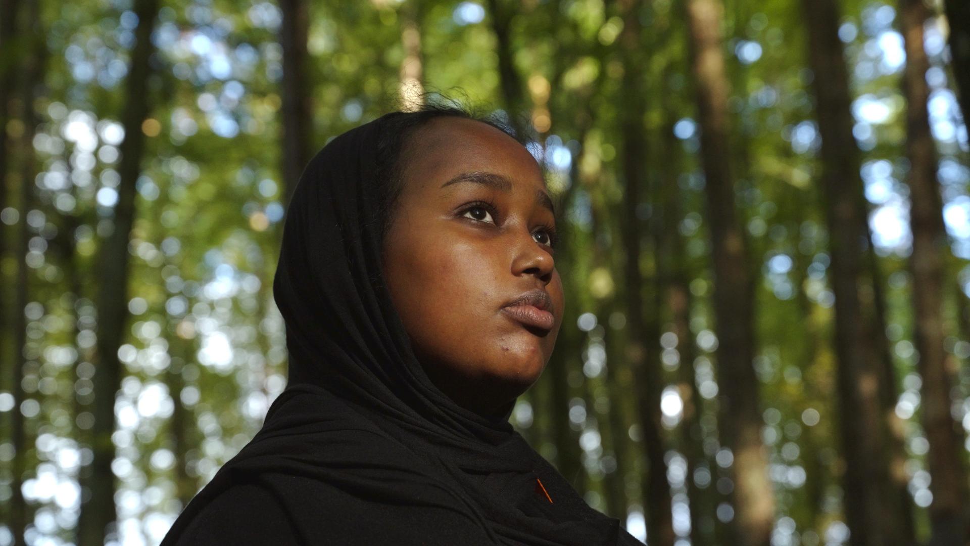 Nahaufnahme der 16 jährigen Sainab steht in einem Wald. 