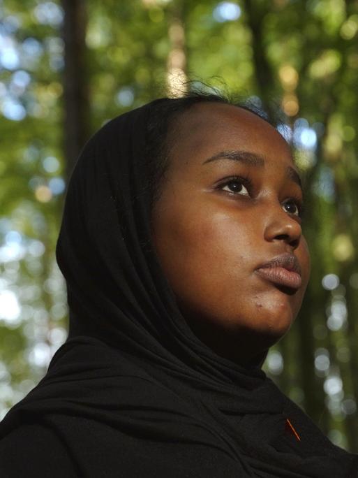 Nahaufnahme der 16 jährigen Sainab steht in einem Wald. 