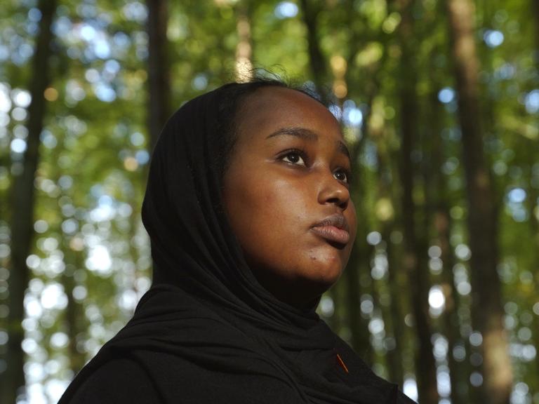 Nahaufnahme der 16 jährigen Sainab steht in einem Wald. 