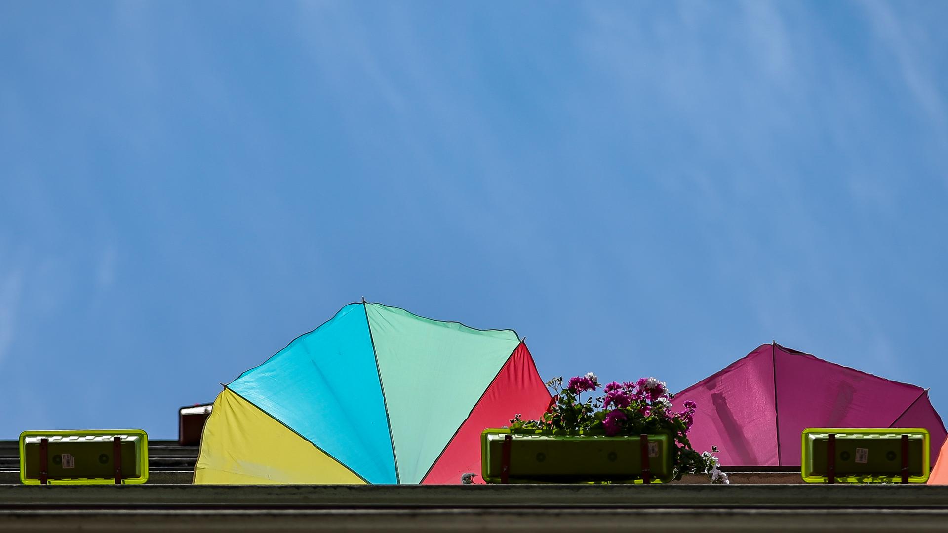 Sonnenschirme ragen über Balkonränder in einer sommerlichen Stadt. Sonnenschirme ragen über Balkonränder in einer sommerlichen Stadt.