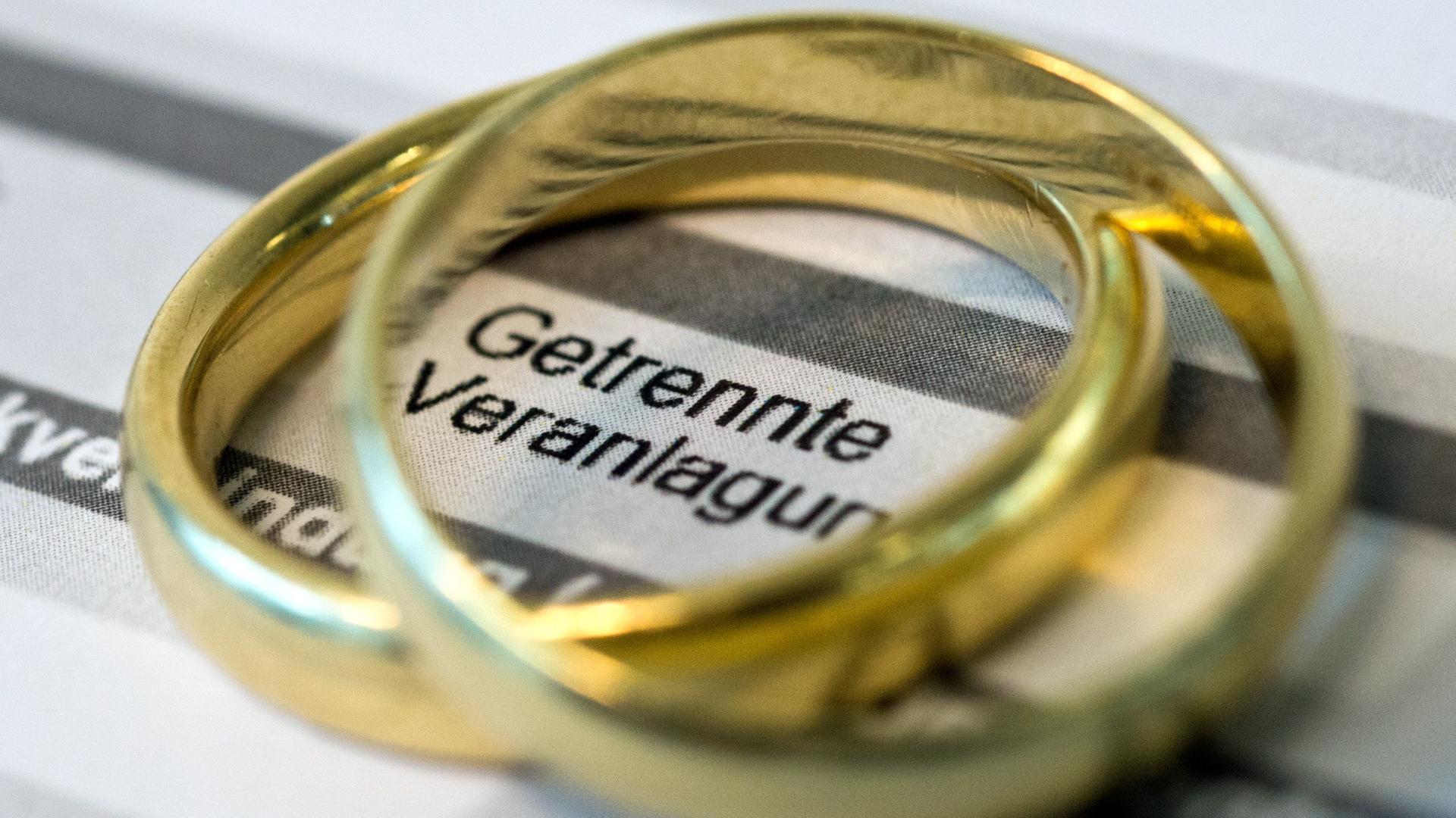 Goldene Eheringe liegen auf Formularen für die Steuererklärung.