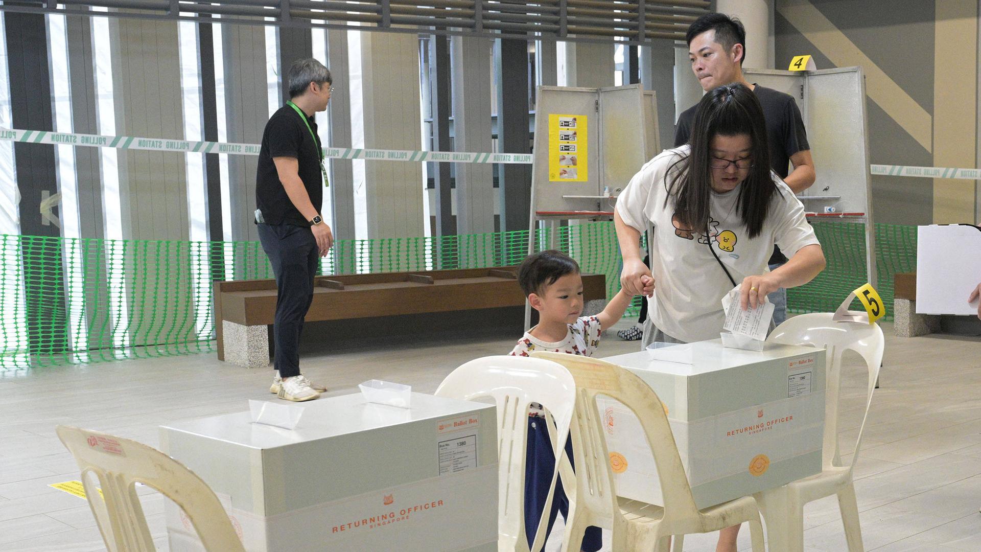 Frau wirft Stimmzettel in Wahlurne in Singapur