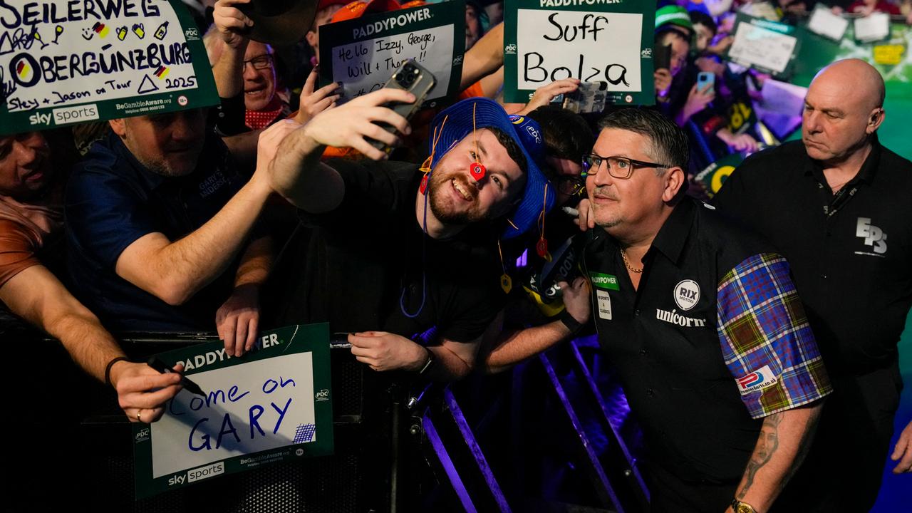 Der Schotte Gary Anderson (2.v.r.) posiert mit Fans während der Darts-Weltmeisterschaft im Alexandra Palace in London. (Foto vom 28.12.2025