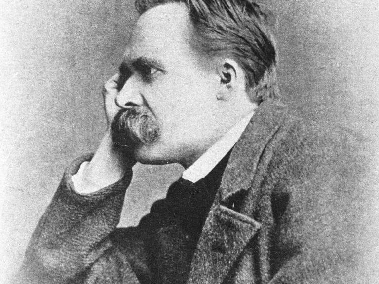 Porträt des Philosophen Friedrich Nietzsche, der seinen Kopf auf seine rechte Hand stützt und grübelnd ins Off des Bildes blickt.