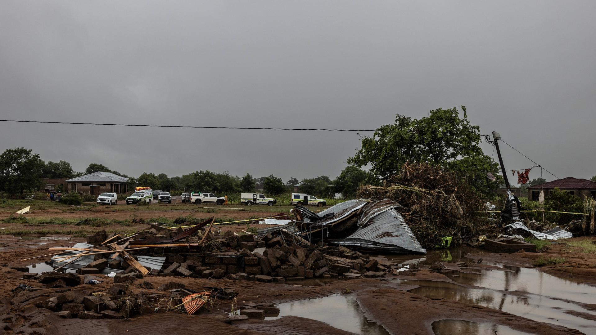 Fahrzeuge von Such- und Rettungsteams stehen neben einem beschädigten Gebäude.